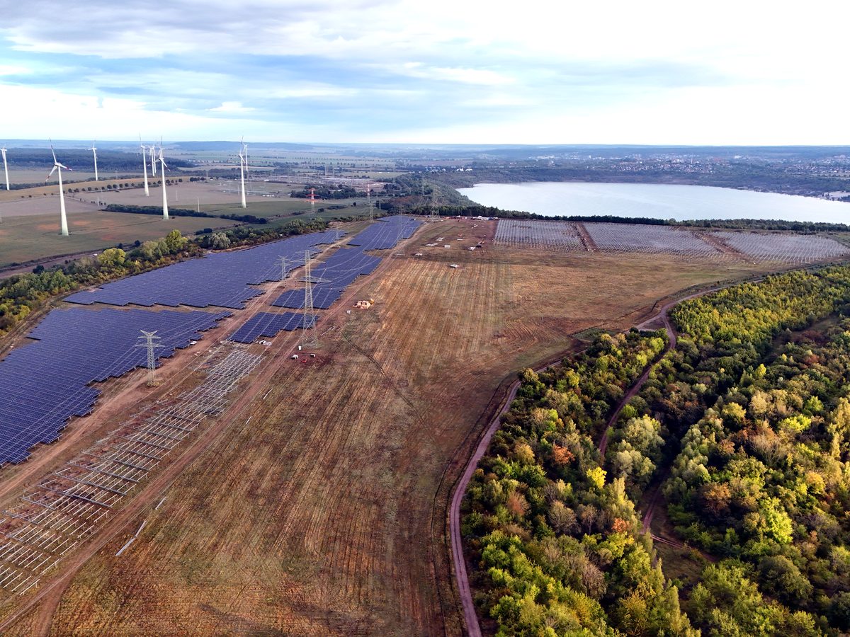 PV farm and wind turbines by the lake — drone photo